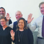 five people waving at the camera