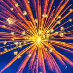 orange and yellow firework explosion against a deep blue sky