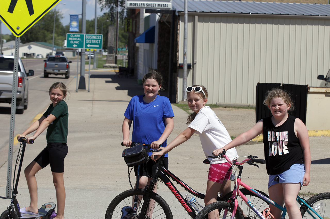 girls riding bike and scooters in summer