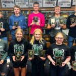 cross country athletes posing with plaques